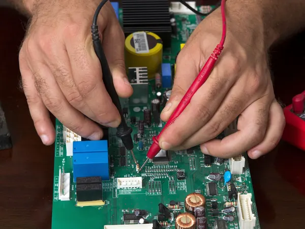 Technician testing an appliance control board with a multimeter